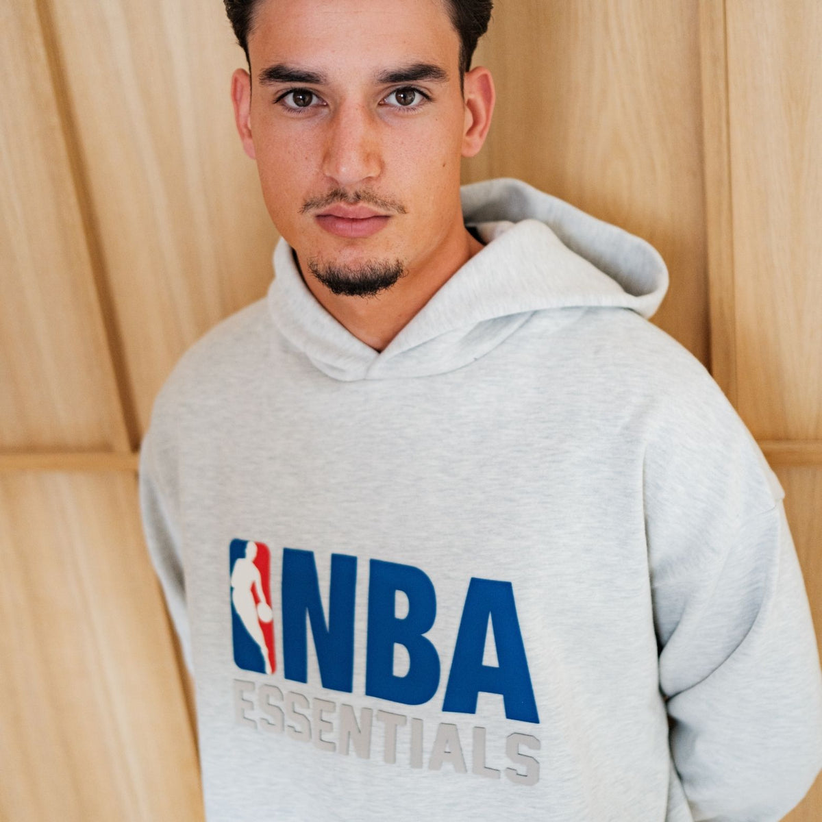 Fear Of God Essentials NBA Light Heather Full set, detailfoto hoodie vooraanzicht met NBA-logo in blauw op grijs