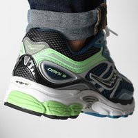 Saucony ProGrid Omni 9 Blue Lime sneakers worn with denim cuffs featuring black silver blue and bright lime green panels with a layered sole