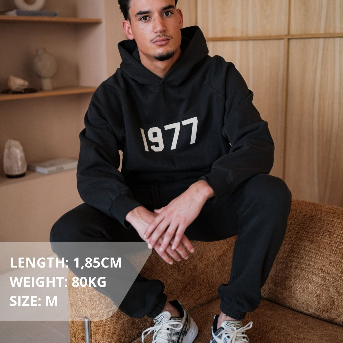 Fear of God Essentials 1977 Iron Black Hoodie, gedragen, zwart sweatshirt met wit '1977' logo op borst