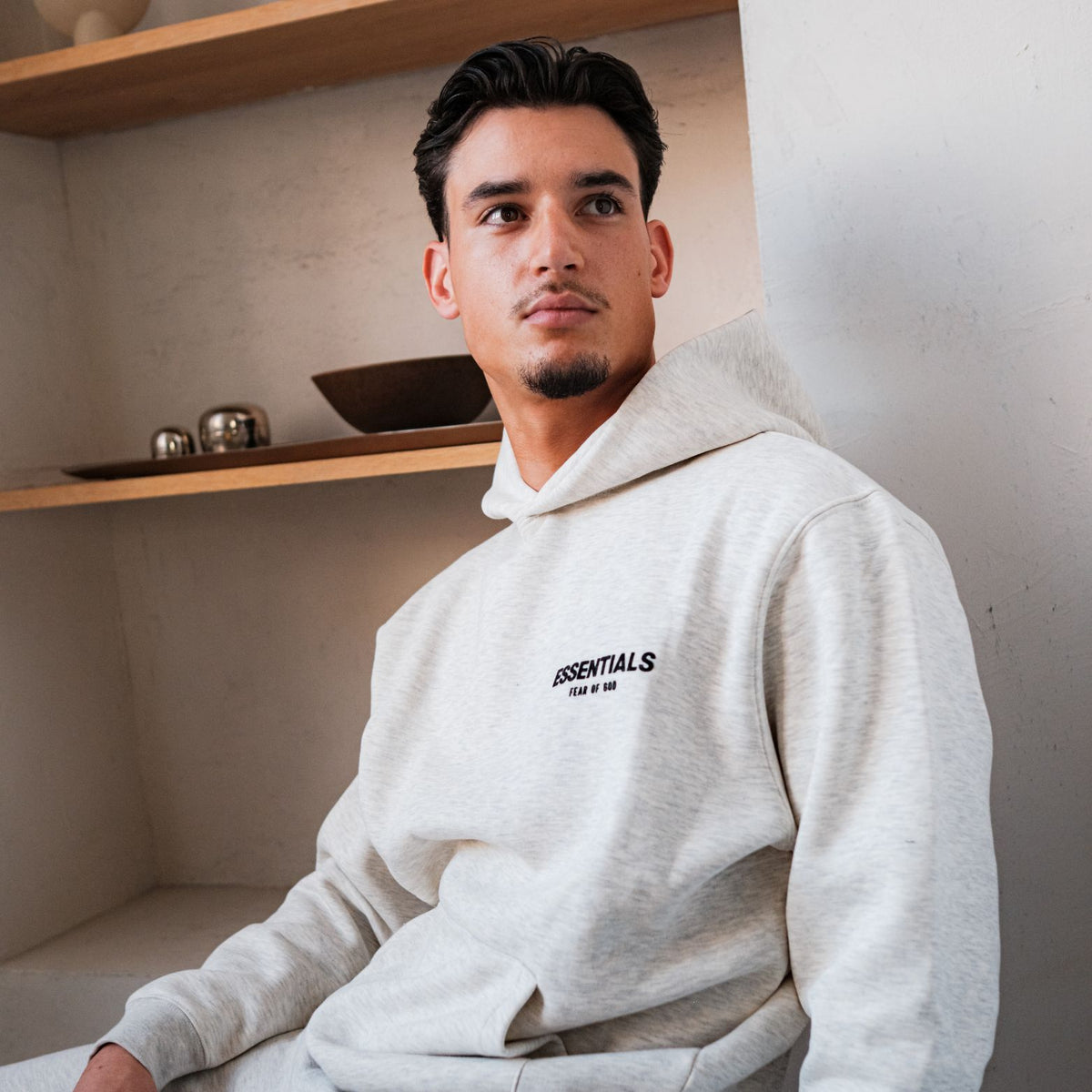 Fear of God Essentials Light Oatmeal Full set, gedragen driekwart aanzicht met hoodie en logo op borst