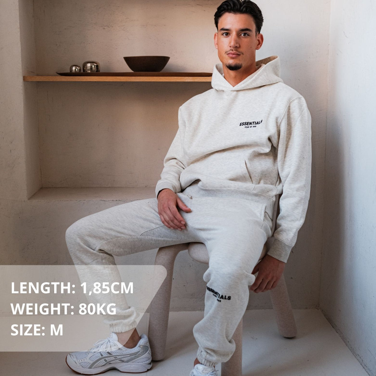 Fear of God Essentials Light Oatmeal Full set, gedragen vooraanzicht met hoodie en joggingbroek in crème, klein logo op borst